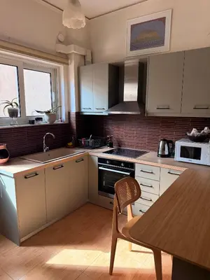 a kitchen with white cabinets and a wooden table at Athens Room in Athens