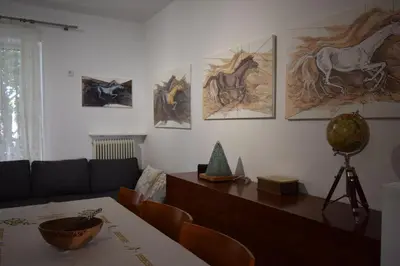 a living room with a table and a couch and drawings on the wall at h2h Dafni #Family home near Athens, airport, ports with garden in Athens