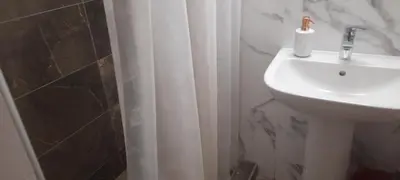 a bathroom with a sink and a white shower curtain at Livia's Room To Ampelokipi metro Airport line in Athens