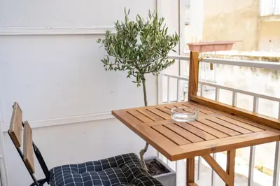 a wooden table and chair on a balcony with a tree at Athens-center 1 bedroom 2 persons apt by MPS in Athens