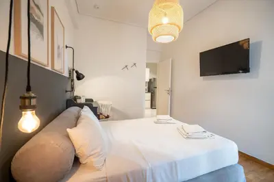 a bedroom with a large white bed and a flat screen tv at Athens-center 1 bedroom 2 persons apt by MPS in Athens