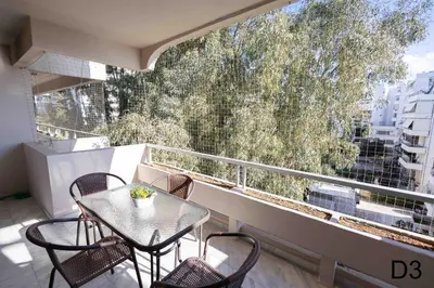 a balcony with a table and chairs and a large window at Sea view apartments in Alimos region in Athens