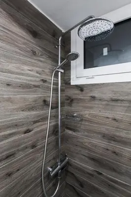 a shower in a bathroom with wooden walls at Plaka's Arch Studio in Athens