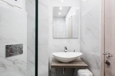 a white bathroom with a sink and a mirror at Plaka's Arch Studio in Athens