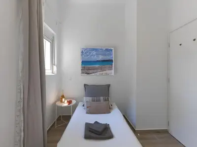 a small white bedroom with a bed and a table at Beautiful Athenian apartment with terrace in Athens