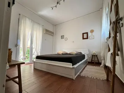a white bedroom with a bed and a window at Athens Taratsaki in Athens