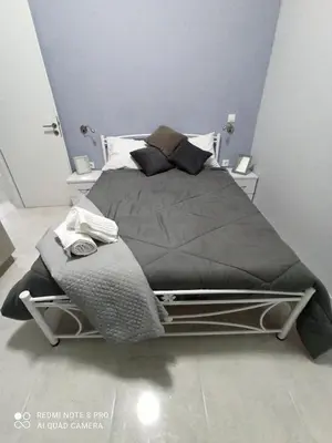 a bedroom with a large bed with grey sheets and pillows at Lovely apartment in the center of Athens. in Athens