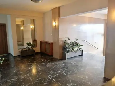 a lobby with a marble floor and two potted plants at Stylish apartment in Acropolis in Athens