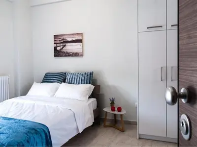 a white bedroom with a bed and a table at Konstantinou Apartment - smart & roof top terrace in Athens