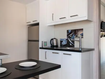 a kitchen with white cabinets and a black counter top at Konstantinou Apartment - smart & roof top terrace in Athens