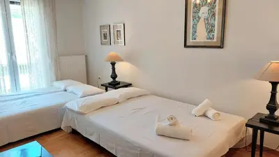 two beds in a room with white walls and a window at Elegant apartment in Acropolis in Athens