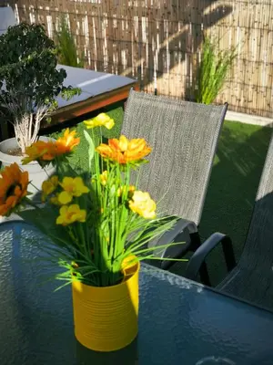 a yellow vase with flowers on a table next to a chair at Group & family penthouse 300m from Agios Ioannis subway,metro station! in Athens