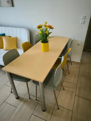 a wooden table with a yellow vase with flowers on it at Group & family penthouse 300m from Agios Ioannis subway,metro station! in Athens