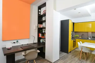 an office with a desk and a kitchen with yellow cabinets at Colorful Apt. Near Nea Smirni Square in Athens