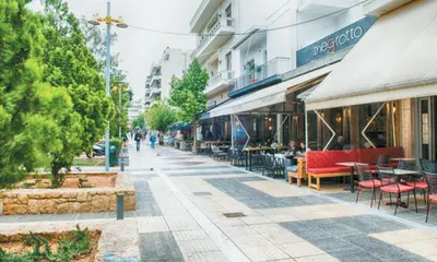 a street with tables and chairs on a sidewalk at Colorful Apt. Near Nea Smirni Square in Athens