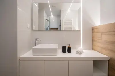 a white bathroom with a sink and a mirror at IO SUITES in Athens