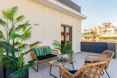 a patio with chairs and a table and palm trees at IO SUITES in Athens