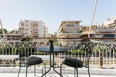 a table and chairs on a balcony with buildings at Remarkable 2BR Apartment in Paleo Faliro by UPSTREET in Athens