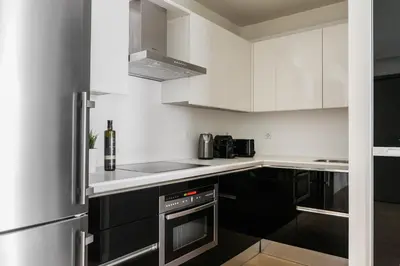 a kitchen with white cabinets and black appliances at Striking Apartments in Kolonaki by UPSTREET in Athens