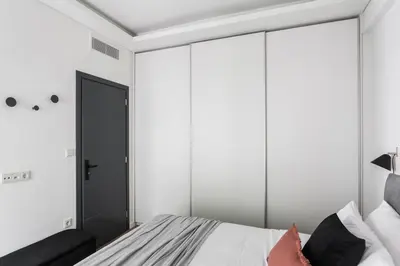 a bedroom with white walls and a bed with a mirror at Striking Apartments in Kolonaki by UPSTREET in Athens