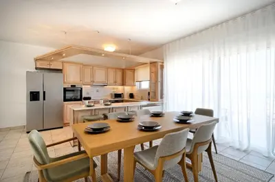 a kitchen and dining room with a wooden table and chairs at Triplex Villa Gardenia Glyfada sea view in Athens