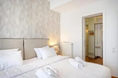 two beds in a bedroom with white sheets and towels at Triplex Villa Gardenia Glyfada sea view in Athens