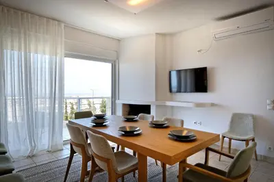 a dining room with a wooden table and chairs at Triplex Villa Gardenia Glyfada sea view in Athens