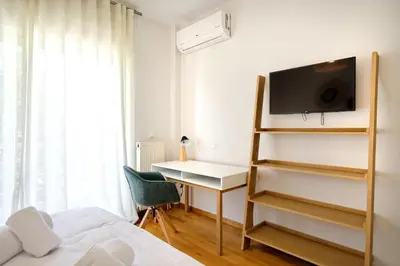 a bedroom with a bed and a desk and a tv at Triplex Villa Gardenia Glyfada sea view in Athens