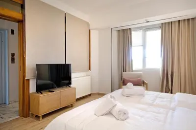 a hotel room with a bed and a flat screen tv at Triplex Villa Gardenia Glyfada sea view in Athens