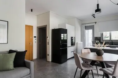 a kitchen and a living room with a table and chairs at Teal Faliro House by UPSTREET in Athens