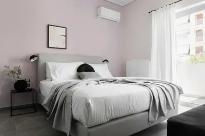 a white bedroom with a large bed and a window at Teal Faliro House by UPSTREET in Athens
