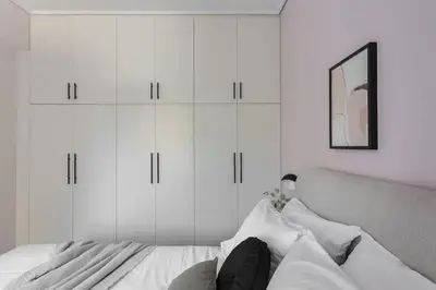 a white bedroom with white cabinets and a bed at Teal Faliro House by UPSTREET in Athens