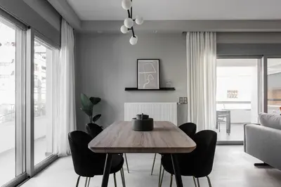 a dining room with a wooden table and black chairs at Teal Faliro House by UPSTREET in Athens