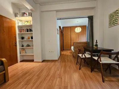 a living room with a table and chairs and a bedroom at Acropolis Museum Suite by YHA in Athens