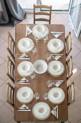a wooden table with plates and wine glasses on it at Blue Riviera villas & suites - Alimos 2 in Athens