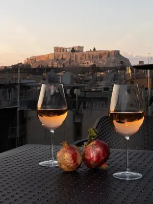 two glasses of wine and pomegranates on a table with a view at Incanto Boutique Suites - Mets in Athens