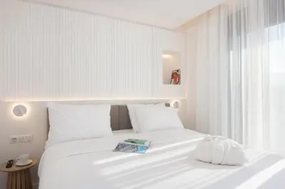 a white bed with white pillows and a book on it at Incanto Boutique Suites - Mets in Athens