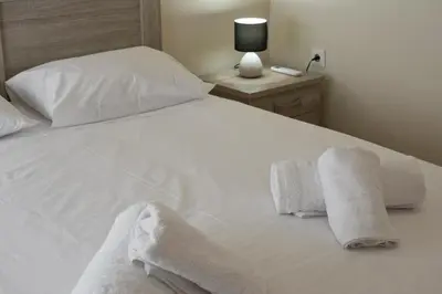 a bed with white sheets and towels on it at Koukaki Gem Cozy 1BR Renovated Apt near Center in Athens