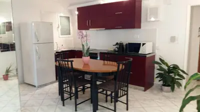 a kitchen with a table with chairs and a refrigerator at Flor de Mayo,Apt in Alimos near the sea in Athens