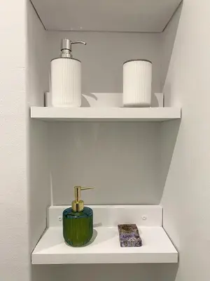 a bathroom with white shelves with a green candle and books at Ermou Studio in Athens