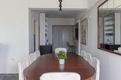 a dining room with a wooden table and white chairs at Seaside Bliss Flat in Saronida