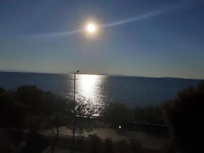 a view of the ocean with the sun in the sky at Seaside Bliss Flat in Saronida