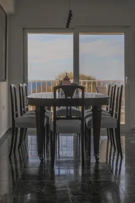 a dining room table with chairs and a window at Seaside Bliss Flat in Saronida
