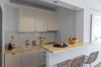 a kitchen with white cabinets and a bowl of fruit on a counter at Seaside Bliss Flat in Saronida