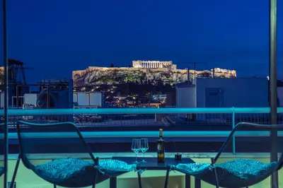 a balcony with two chairs and a table with wine glasses at Acropolis View Mini Sky Suite & Hot Tub in Athens
