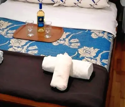 a bed with two rolled towels and a table with wine glasses at Kalamaki Guest House in Athens