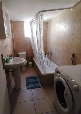 a bathroom with a tub and a sink and a washing machine at Kalamaki Guest House in Athens