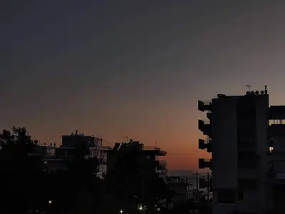 a city skyline at sunset with buildings in the foreground at Kalamaki Guest House in Athens