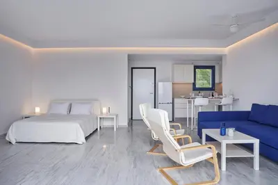 a bedroom with a bed and a blue couch at Augoustos ECO luxury apartments with pool in Aghia Marina