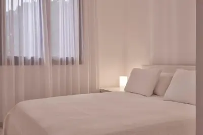 a white bed with white pillows and a window at Augoustos ECO luxury apartments with pool in Aghia Marina